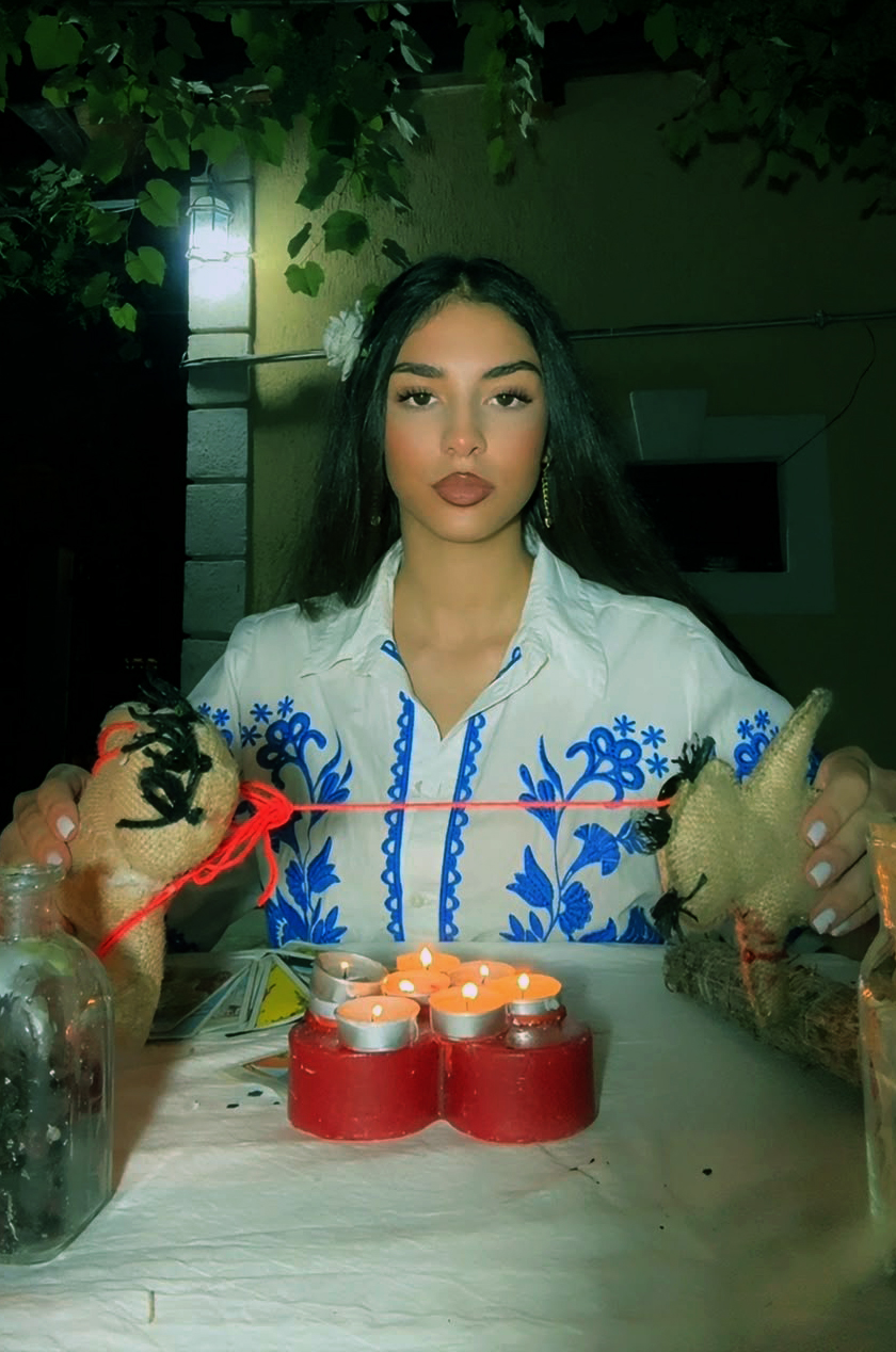 Vrăjitoarea Andra Aida în ie tradițională, la masa de ritual cu lumânări
