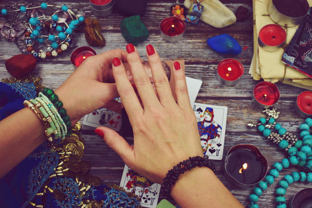 Mâini deasupra cărților de tarot și a obiectelor de ritual